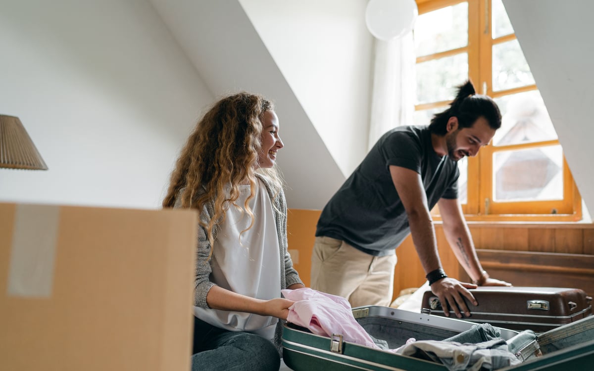 Young couple smiling and packing suitcases together while preparing to move abroad